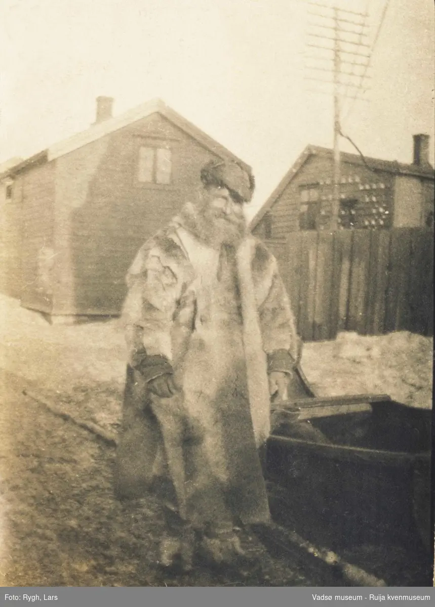 Mann i samisk pesk ved siden av en slede. Ant. i Vadsø. 1917-1918