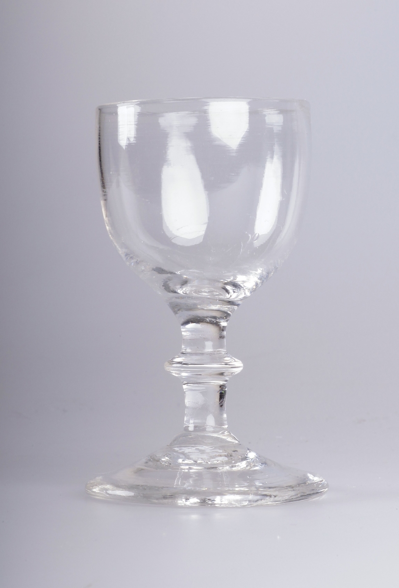 Stettglass blåst i tre deler, med klokke, stett med skive og konkav fotplate. Brutt pontemerke/puntelmerke under. Antatt produsert på Gjøvik Glassverk (1807-1843)
