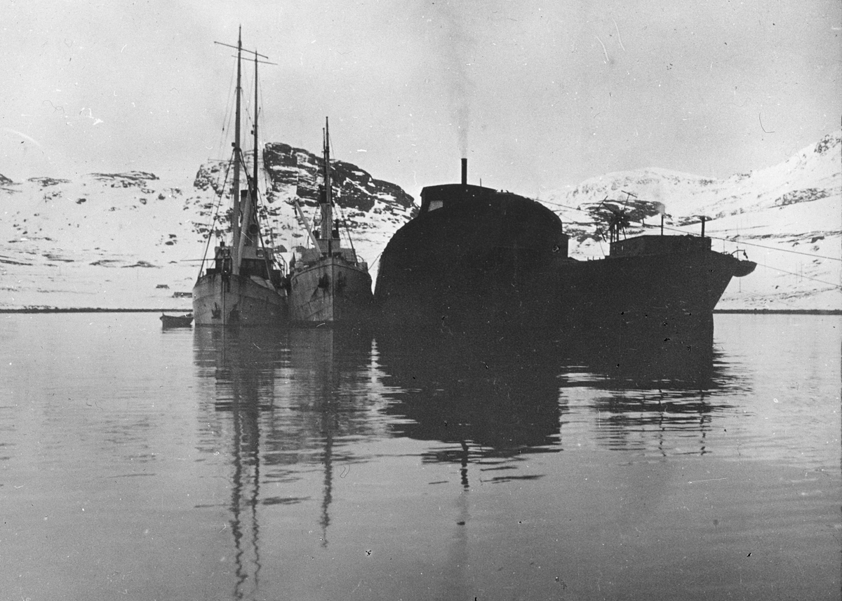 To dampskip og en robåt ligger ved siden av to opphugningsskip i en snødekket fjord.