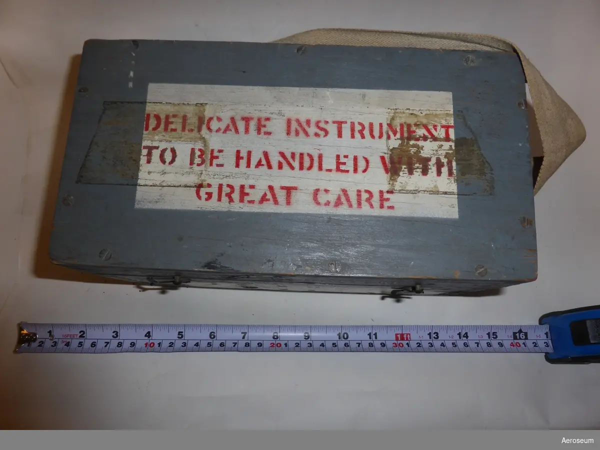 en Astrokompass i en grå trälåda. Serienummer är 11592. På lådan går det att läsa "ASTRO COMPASS MKII". På locket, lådans framsida och baksida står det med röda bokstäver och vit bakgrund "DELICATE INSTRUMENT TO BE HANDLED WITH GREAT CARE".

På insidan av locket finns det en stämpel som ger årtalet 1944 och en papperslapp där det står: "PACKING" och "SET COURSE TO "S" AND LAT. TO "9" AND PLACE IN BOX WITH LEVELS DOWN".