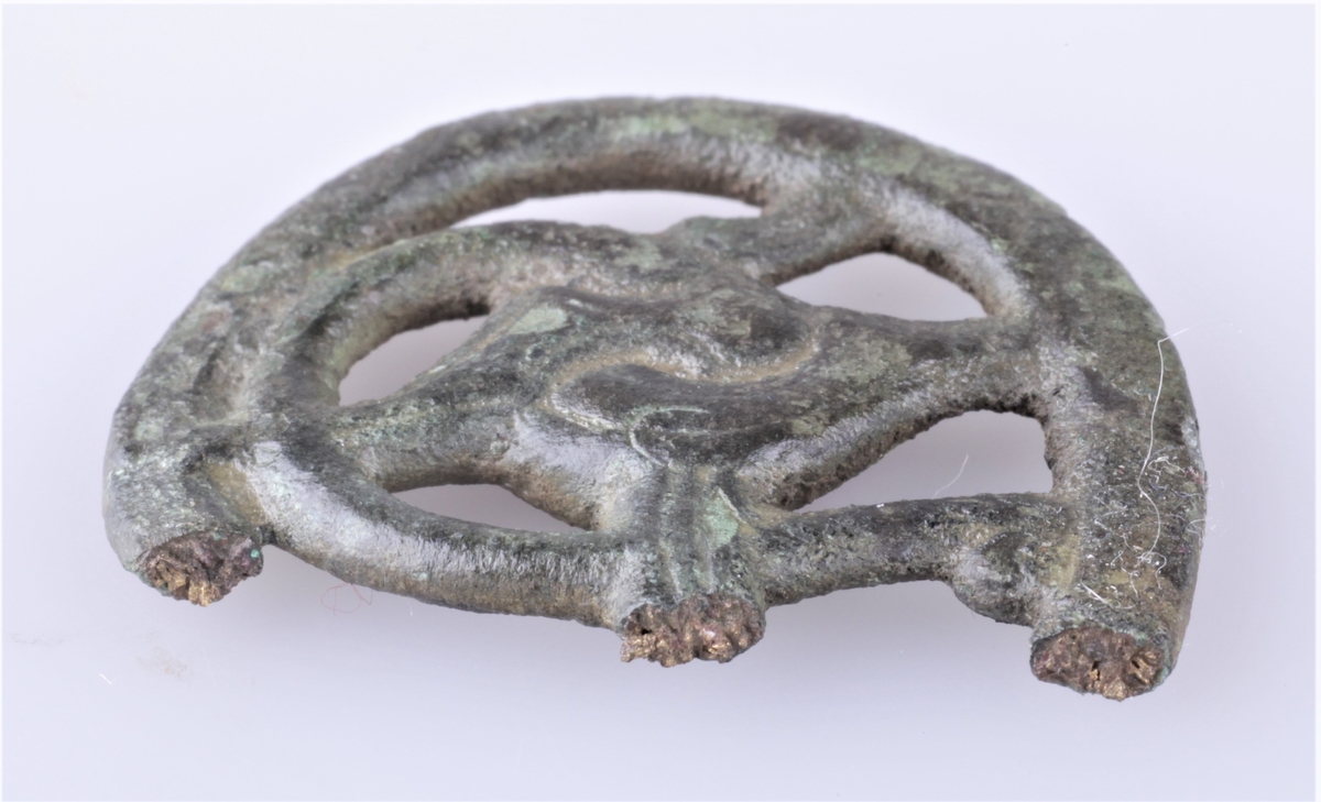 Nøkkelskaft støpt i bronse med gripedyrsmotiv. To deler; a) hoveddelen har avlang buet form, b) del falt av hoveddelen.