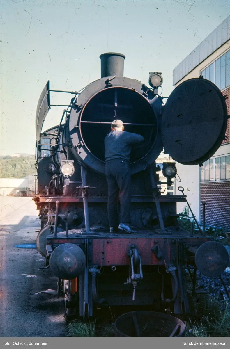 Damplokomotiv type 30a nr. 274, en lokomotivstallbetjent tømmer røykskapet for stubb.