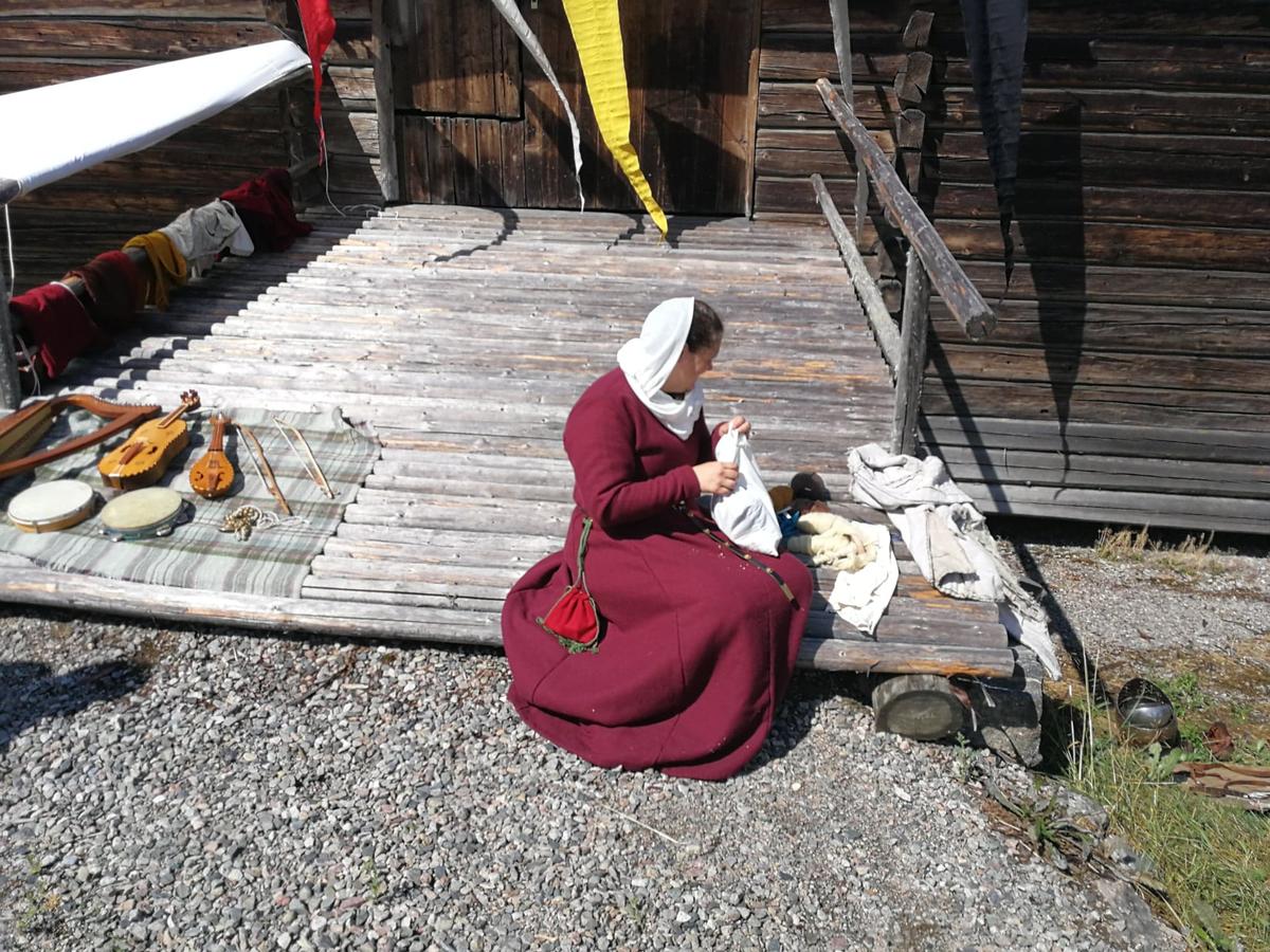 En kvinne har satt seg på låvebrua med sytøyet sitt under Middelalderdagen på Almenninga (Foto/Photo)