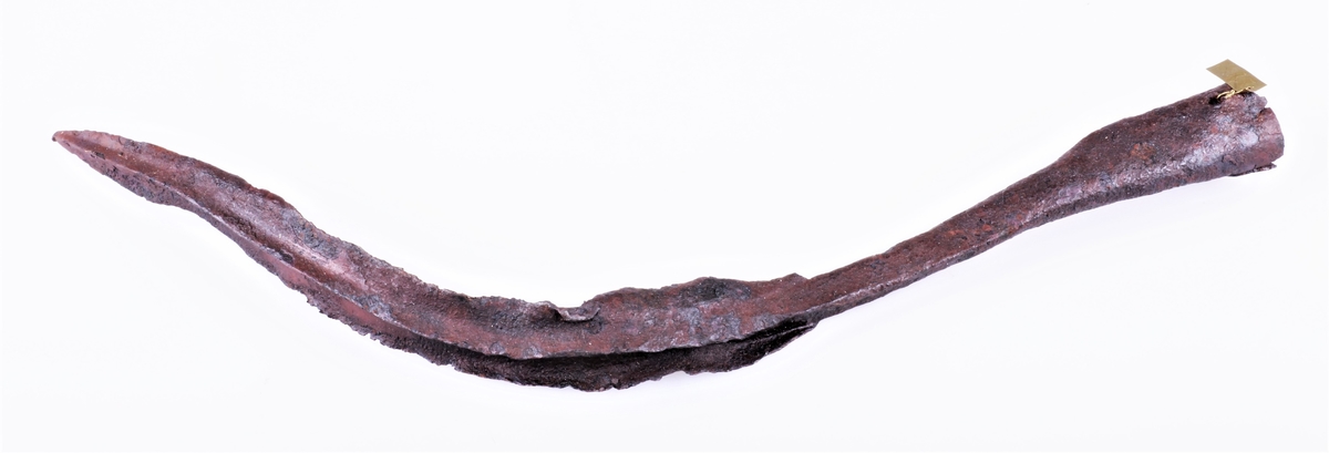 En bøyd spydspiss av jern med opphøyd rygg langs midten på bladet, på begge sider. Funnet i Vang i Valdres.