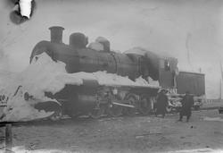 Sydvarangers lokomotiv full av snø, to arbeidere nede på bak