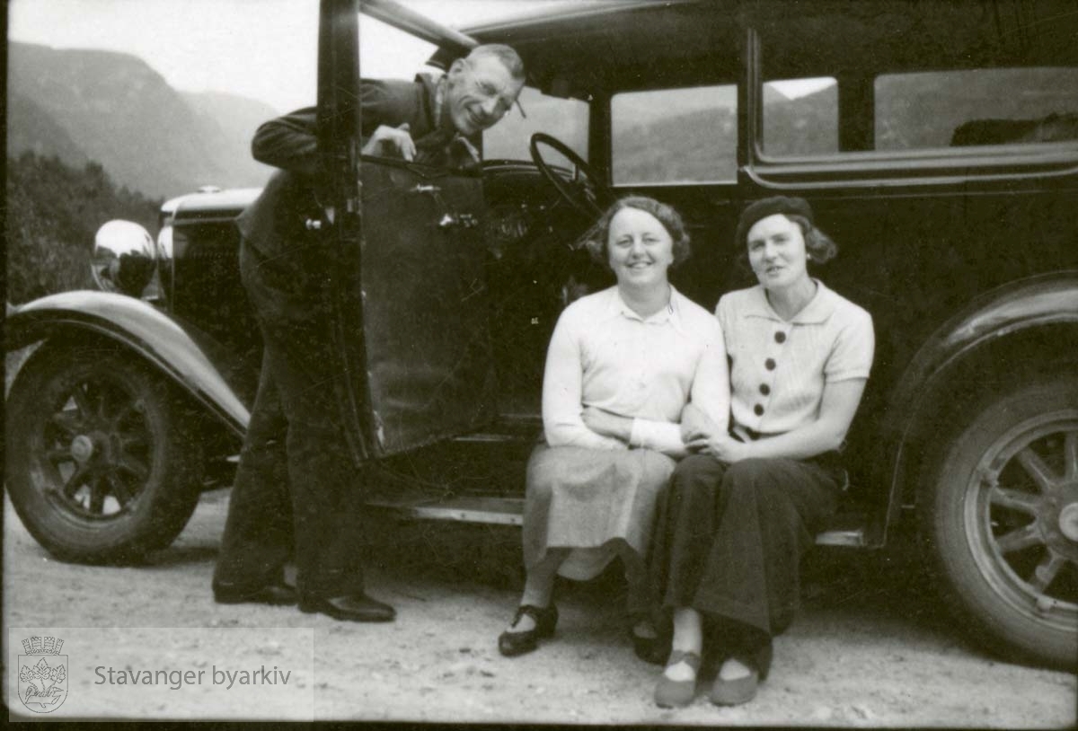 Bil, to kvinner sitter i døren som holdes oppe av sjåføren
