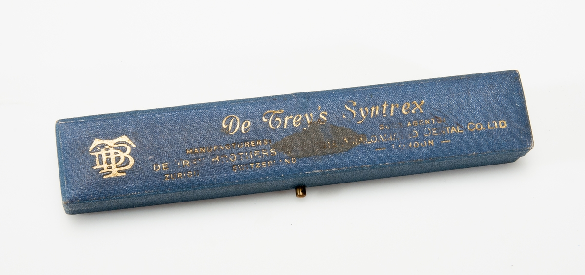 Färgskala som ligger i en blå läderlåda. Har texten "De Trey Syntrex" i guldfärg på sig. Resten av texten är svårläst. 1900 talet.