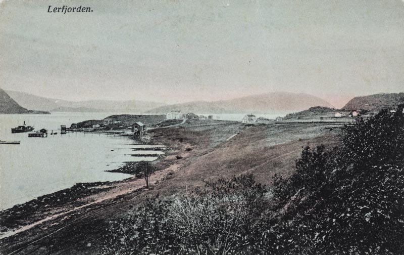 Leirfjord, Nedre-Leland. Oversiktsbilde av landskapet. Bildet er tatt mot Bergh-brygga (museum) med Breivika i bakgrunnen. Bildet er kolorert. Finnes også i s/hv som LEF.F.00086