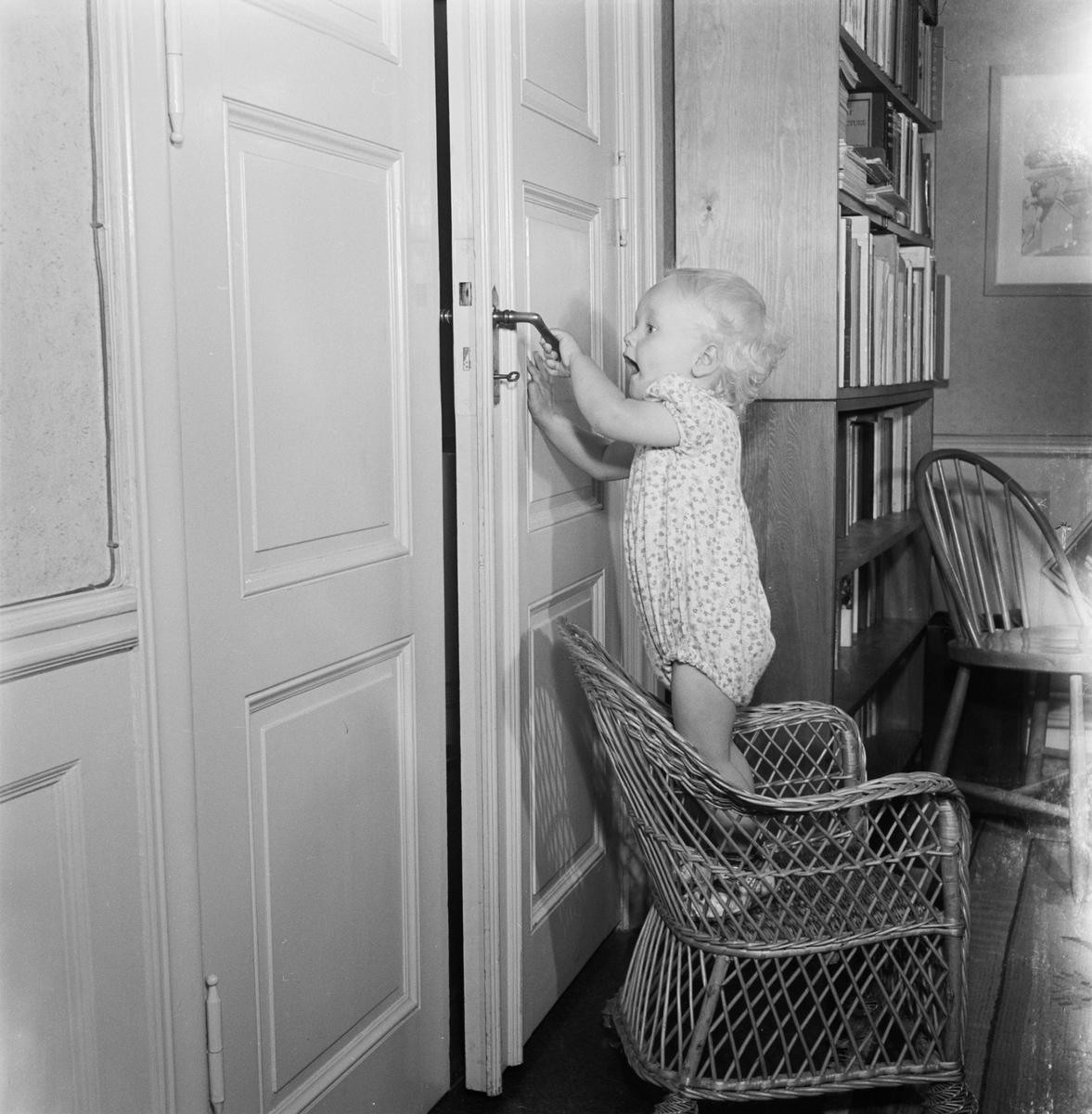 Pojke står i korgstol vid dörr, Uppsala 1952