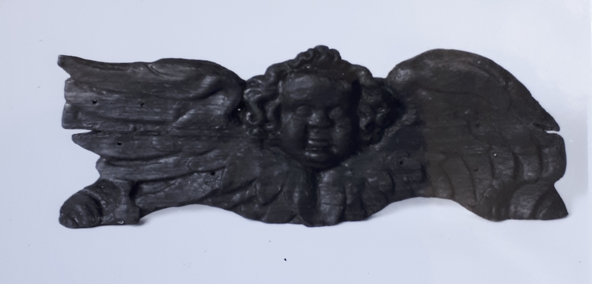Skulpterat änglahuvud med vingar.
