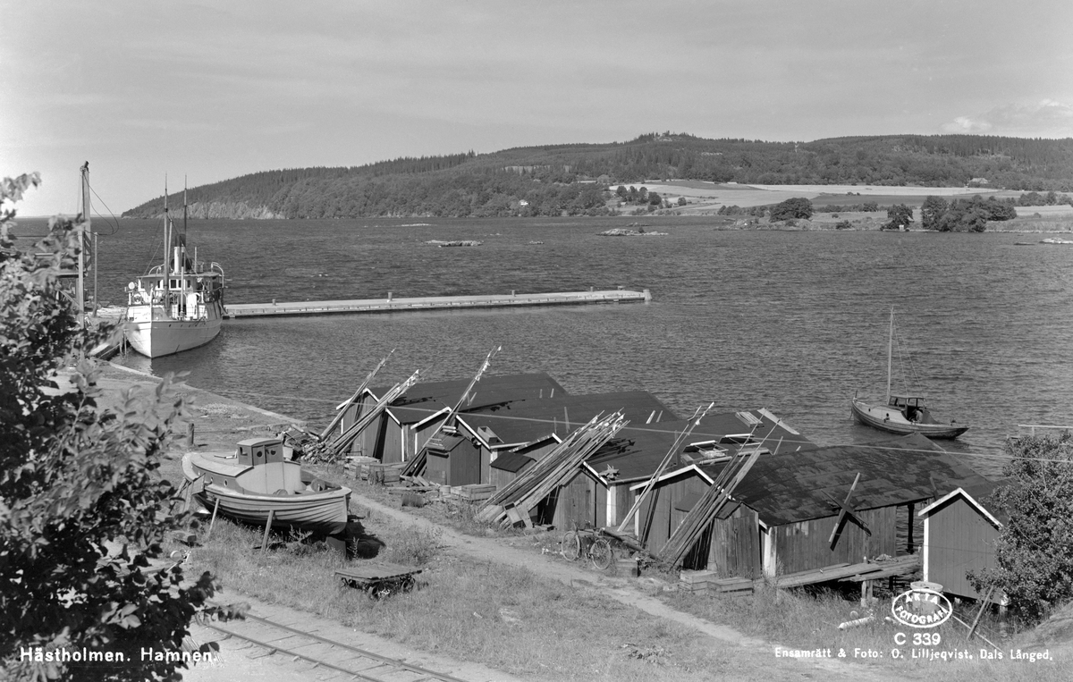 Vy över hamnen i Hästholmen. Till vänster ligger ångaren S/S Trafik som från 1892 till tiden för bilden gått på traden Hjo-Hästholmen. I bakgrunden höjer sig Omberg.