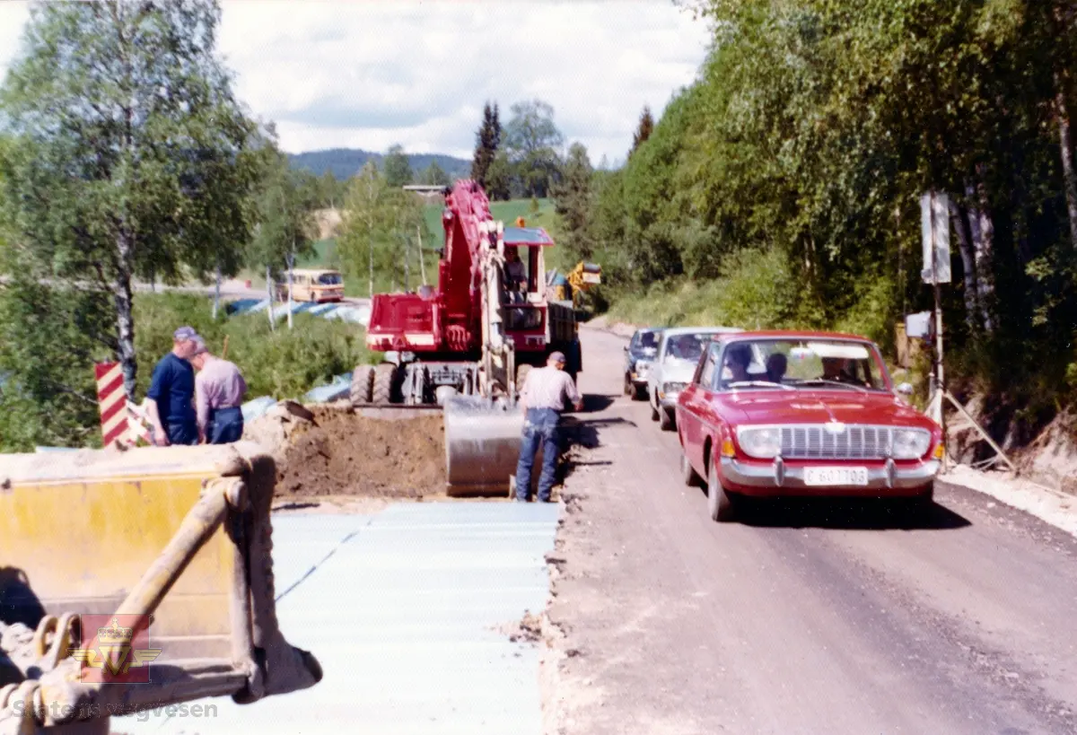 Forsterkning og frostsikring av tidligere Hallingdasvegen (Rv 7) ved Sandaker. Tidspunkt, rundt 1972. Isolasjonsplater av ekstrudert polystyren nær opp mot vegbanen førte til isingsproblem. Fremst Rød Ford Taunus fra midten av 1960-tallet.