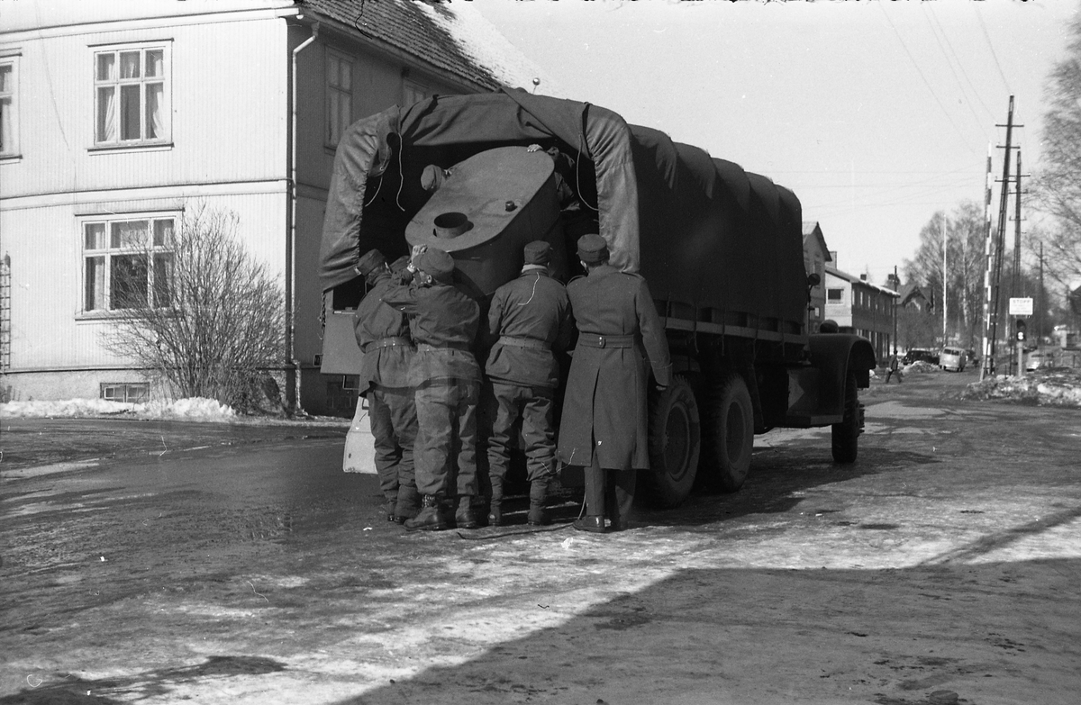 To bilder fra Lenagata mars 1958. Noen soldater holder på å lesse av eller på en militær lastebil noe som kan se ut som del av et feltkjøkken.