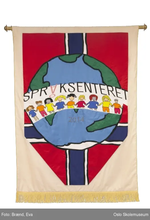 Et norsk flagg, en jordklode og en rekke med elever hånd i hånd. Motivet skal illustrerer norsk skole og elevene som kommer fra hele verden til Språksenteret. På jordkloden står året skolen ble etablert.