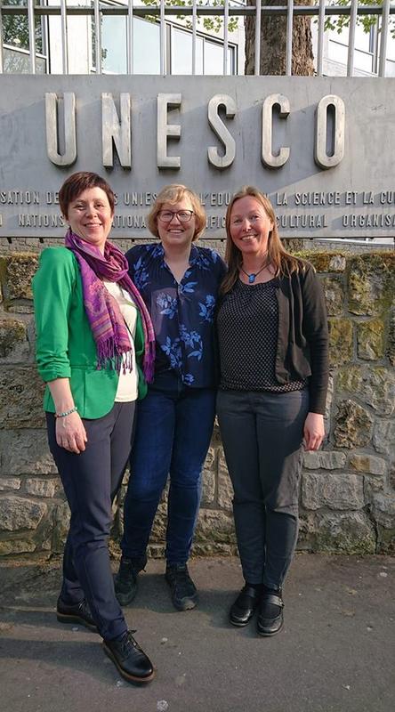 Tre kvinner foran skilt med UNESCO