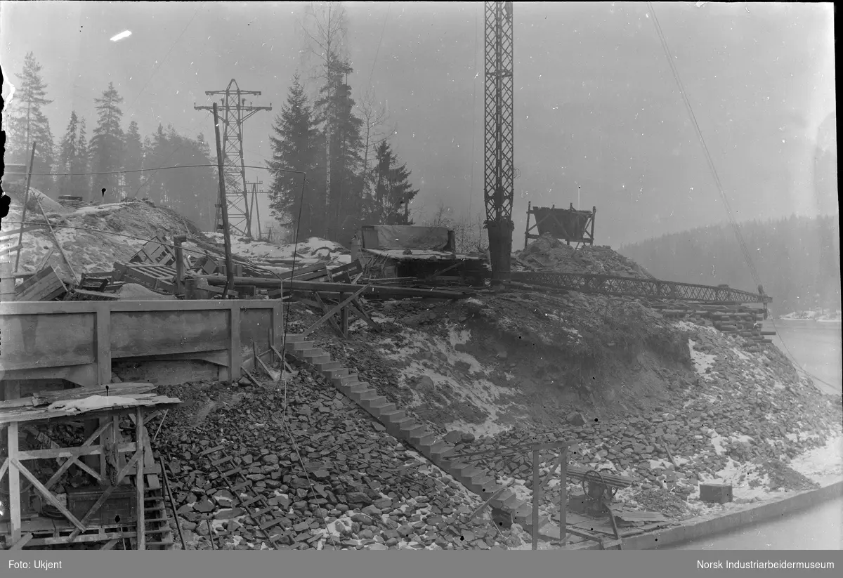 Anleggsarbeid under bygging av Labro Kraftstasjon. Kran og trapp ned til elvebredden.