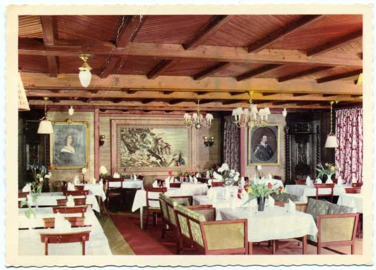 Interiör från Ribbagårdens matsal med historiska porträtt på väggarna och bord dukade med glas och servetter.