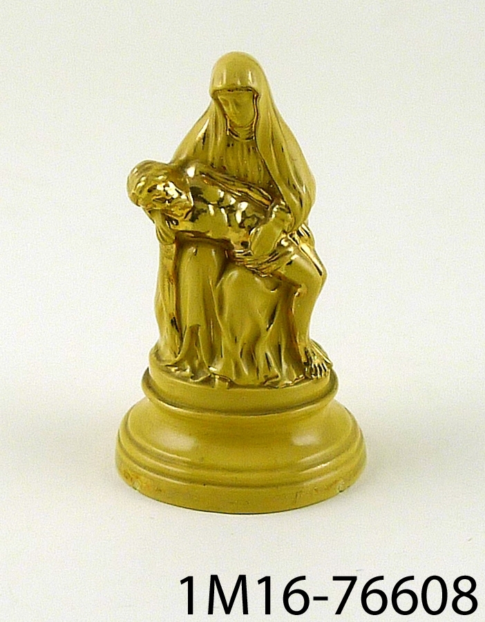 Figurin med pietà-motiv (ett tema för kristen konst som avbildar en sörjande Jungfru Maria vid sin döde sons kropp). Figurinen har glasyr i gult och detaljer målade i guld.