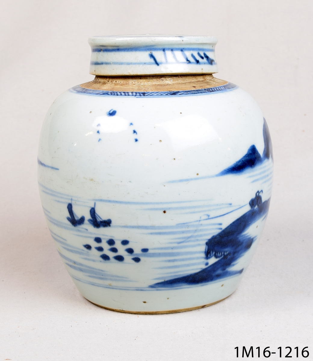Rund urna med lock. Den är kinesisk och har vit glasyr med blå handmålad dekor föreställande bland annat ett landskap. En bojan, en burk för förvaring av ingefära.