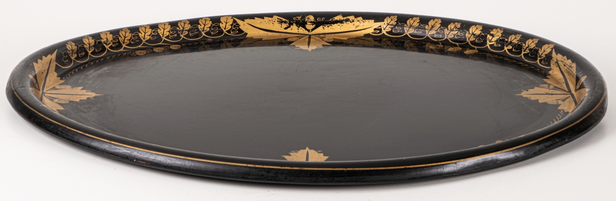 Bricka plåt oval svartlackerad, ekollon i guld runt kanterna, bredd 63 cm, mitt på litograferad bild, jägare, vallflicka, getter.
