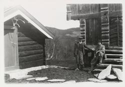 En mann står og en mann sitter ved loftet på tunet på Sundet