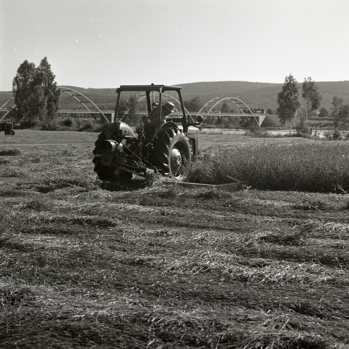 En person utför slåtterarbete med traktor i Hammar, Nyland.