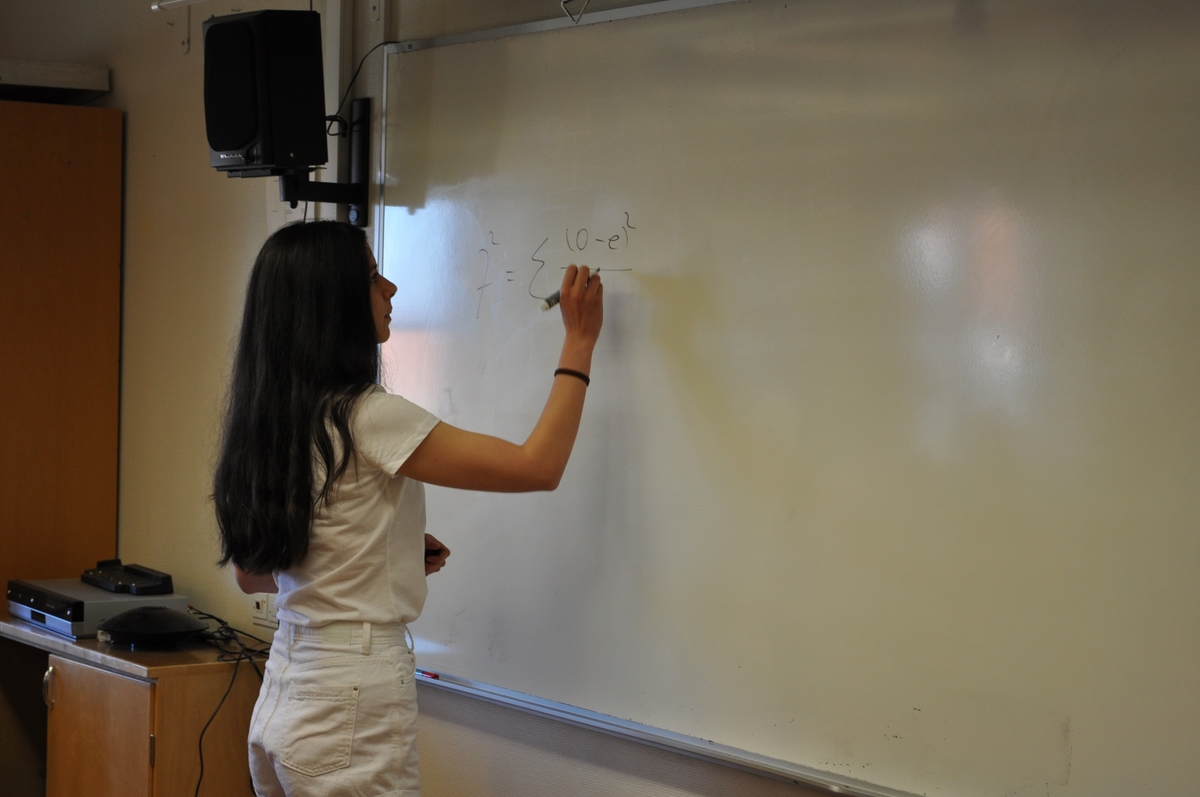 Läxförhör i biolog/matematik i samband med studenten. Eleven Biana Baiatu i vita shorts och vit t-shirt skriver på vita tavlan och redovisar en matematisk fråga kring statistik.