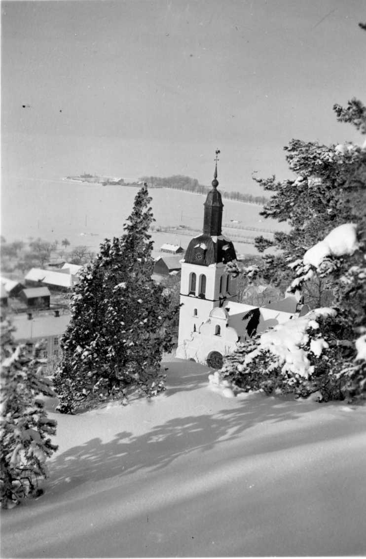 En vy från Grännaberget, vintertid, med Gränna kyrka i centrum. Vättern är frusen och snötäckt.