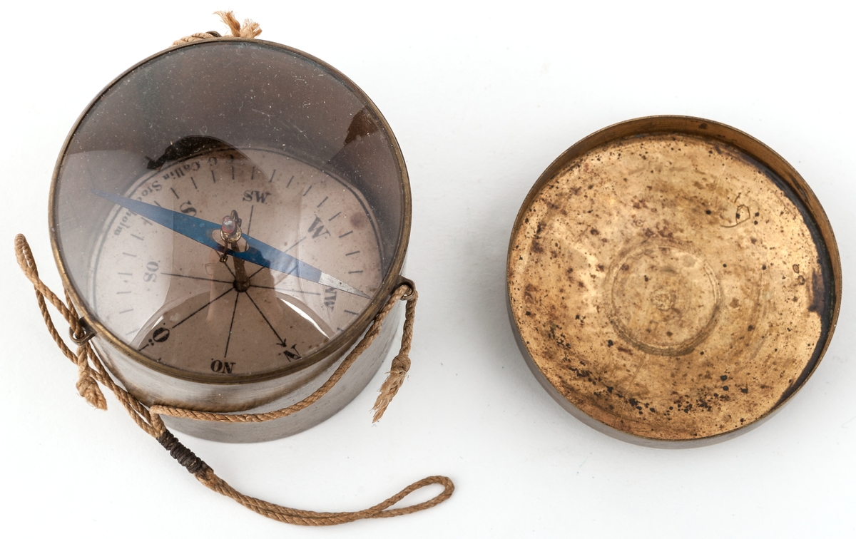 Kompass i cylindriskt mässingsfodral, upphängningsbar. Höjd 6 cm, diameter 6 cm.
Från firma C. G. Collin, Stockholm.