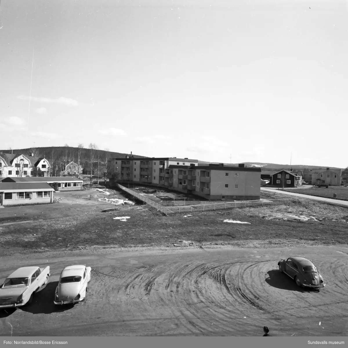 Flerfamiljslänga vid Centrumgatan 22-30. första bilden syns delar av Matfors skola till vänster och bakom björkarna byggnaden där Norrlands Bank huserade samt Röhmans affär, båda rivna. På andra bilden syns gamla bankhuset till höger.