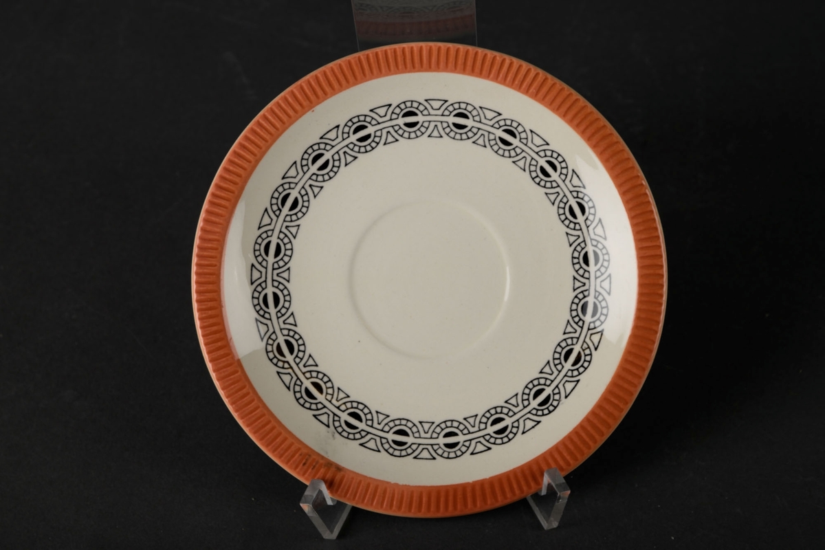 Hvitt tefat med orange bølgete kanter, og dekorert med mønstre rundt midten.
