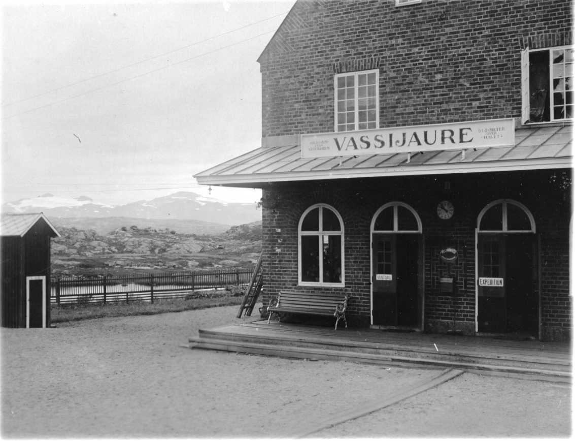 Järnvägsstationen i Vassijaure. En tegelbyggnad med skylt "VASSIJAURE" ovan två dörrar märkta "VÄNTSAL" respektive "RECEPTION".
