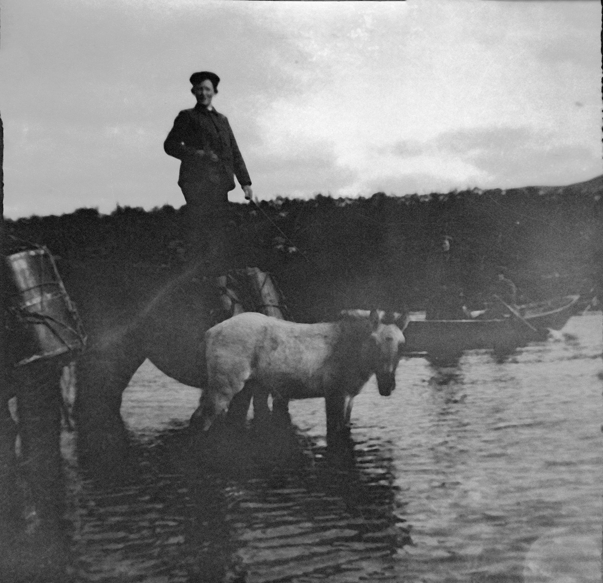 Gutt med hest og vogn krysser vann