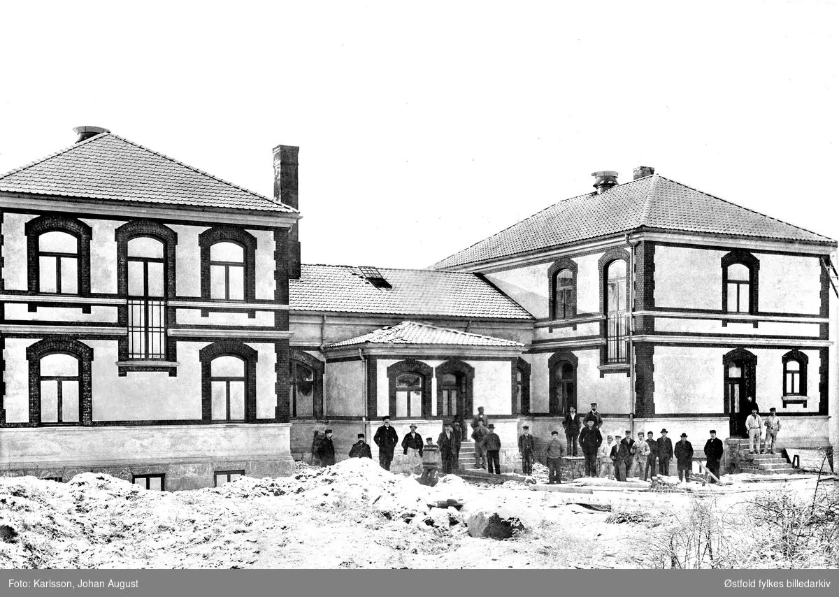 Sarpsborg sykehus under bygging, 1901. Råbygget er ferdig og arbeiderne står foran bygningen.
