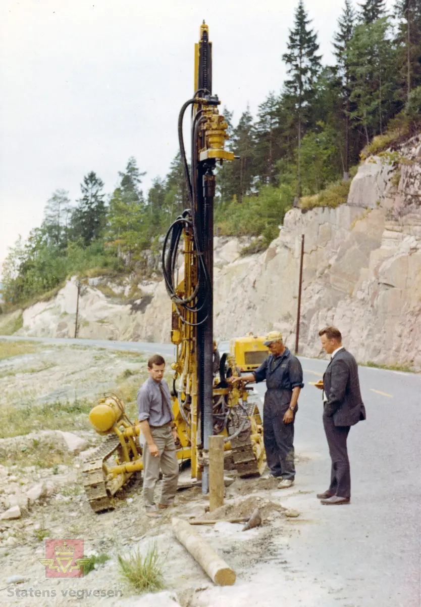 Borrigg monterer rekkverksstolper langs veg i 1968. Ukjent sted i Buskerud.