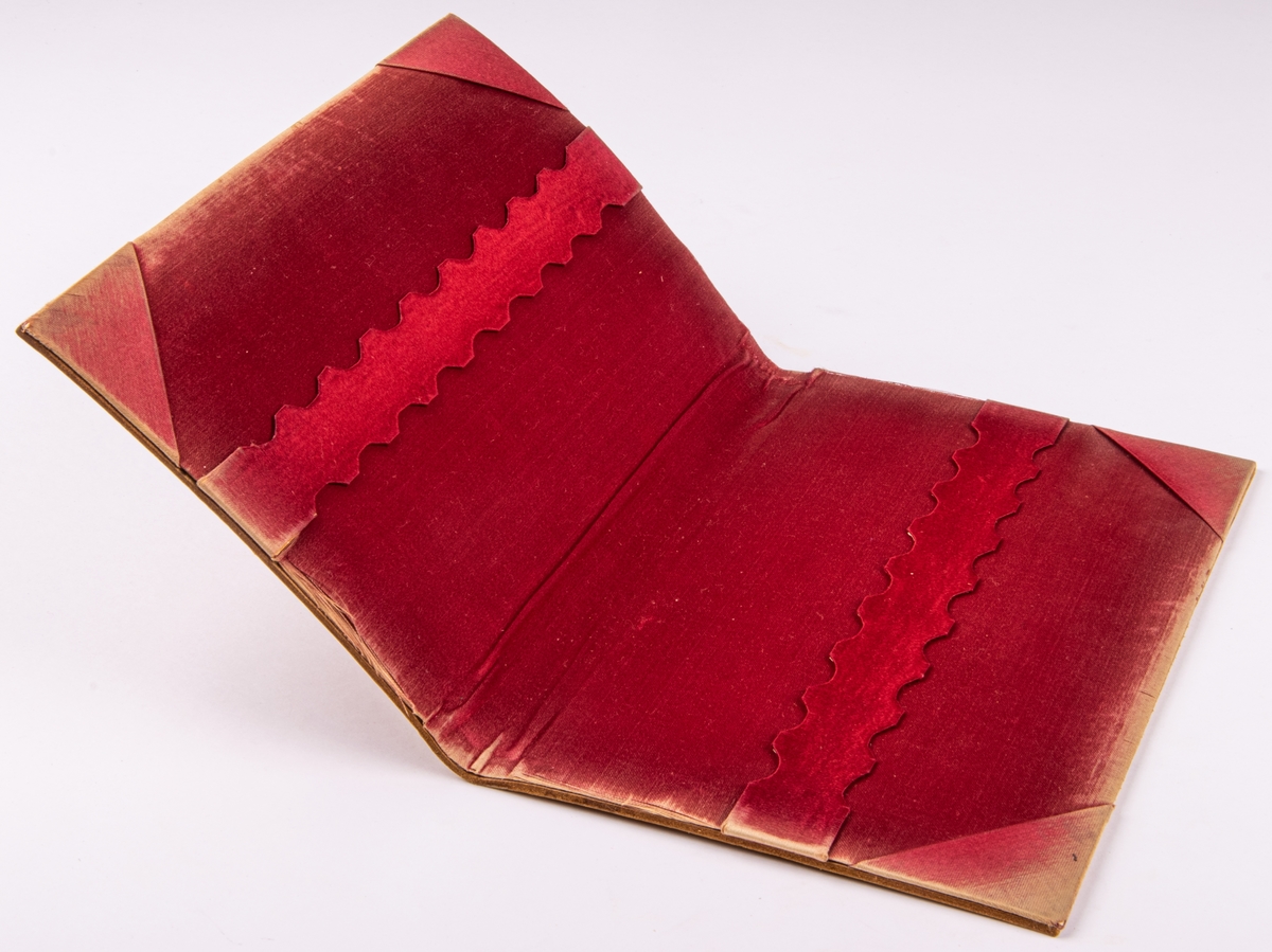 Bokpärm, läderplastik, utförd av John Runer. Ljust läder. Klädd med rött tyg.
