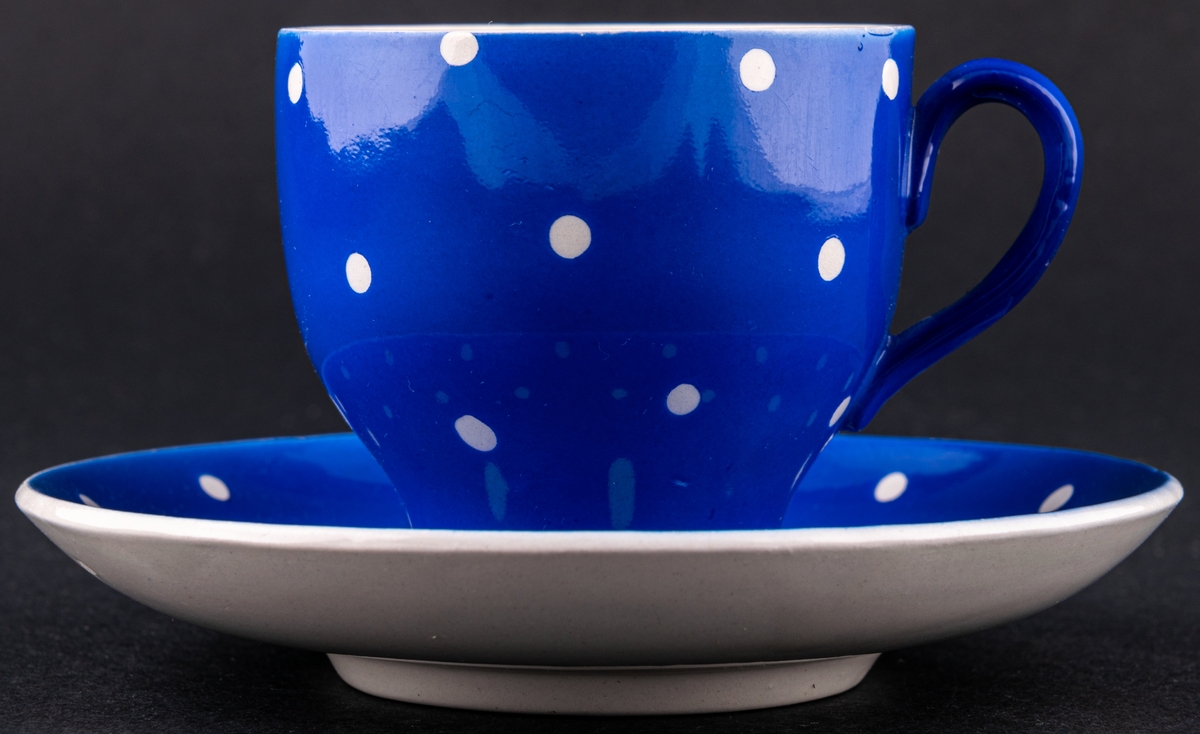 Kaffekopp med fat, modell AX i dekoren Amanita, den blå varianten med vita prickar. Dekoren skapad av verkmästare för dekoravdelningen Helmer Ringström.