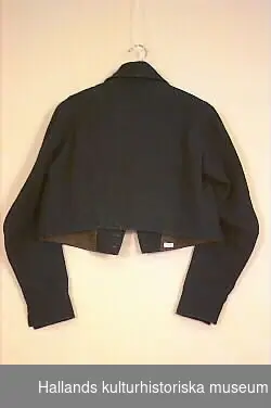 Rock med mörkblå, svarta överklädda knappar.Längd från axeln 47 cm. Vidd i underkant 110 cm. Material: Textil, bomull, ull, blaggarn, werken.