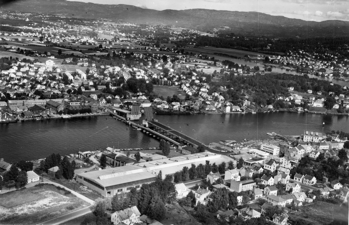 Flyfotoarkiv fra Fjellanger Widerøe AS, fra Porsgrunn Kommune. Porsgrund Metallverk A/S, Gamle og nybrua ligger paralellt. Fotografert 04.09.1957. Fotograf A. Holm