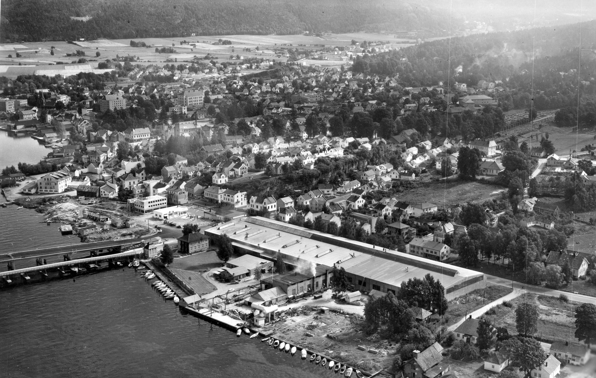 Flyfotoarkiv fra Fjellanger Widerøe AS, fra Porsgrunn Kommune. Porsgrund Metallverk A/S, Gamle og nybrua ligger paralellt. Fotografert 04.09.1957. Fotograf A. Holm