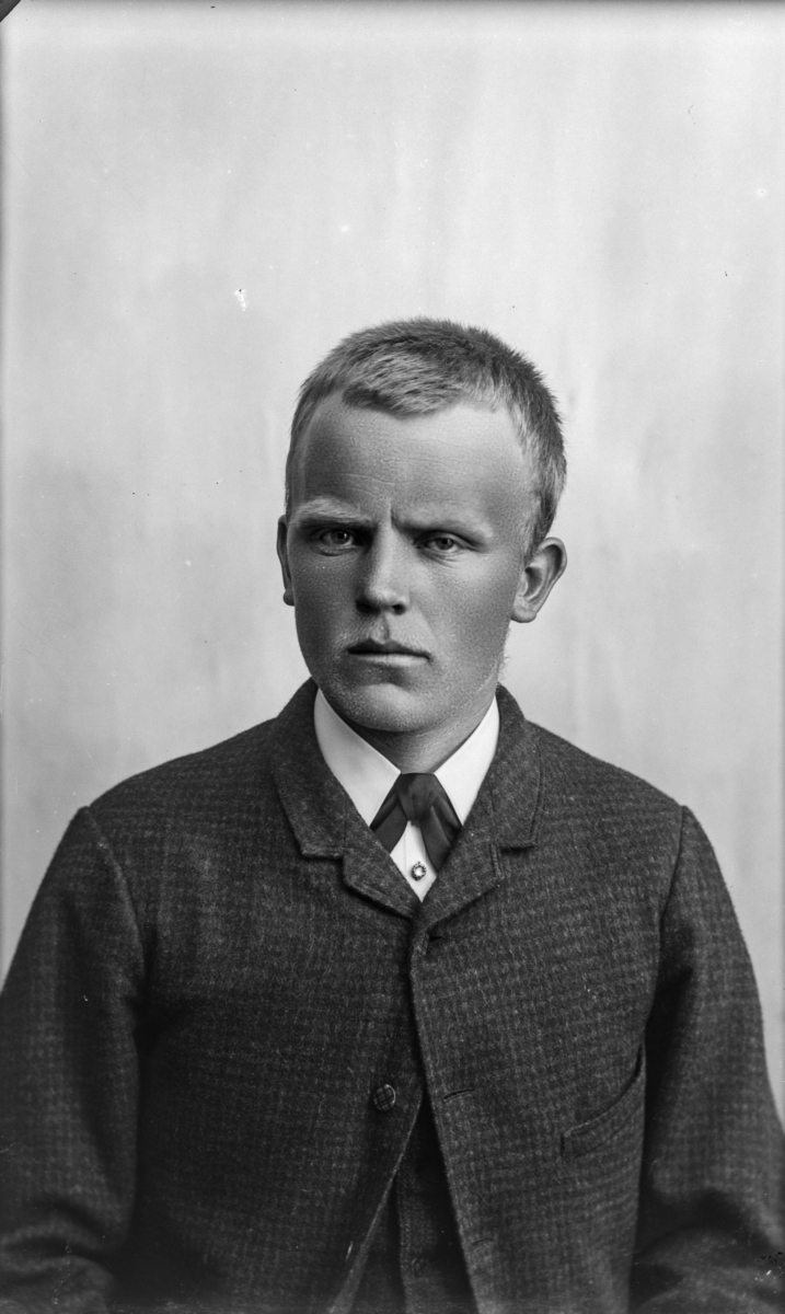 Portrett av yngre mann med blondt, kort hår kledd i kvit sjorte og mørk jakke