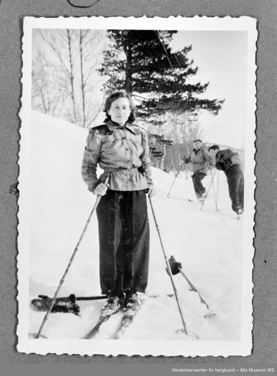 3 personer på skitur i 1936 med datidens skiantrekk og et stort furutre i bakgrunn.