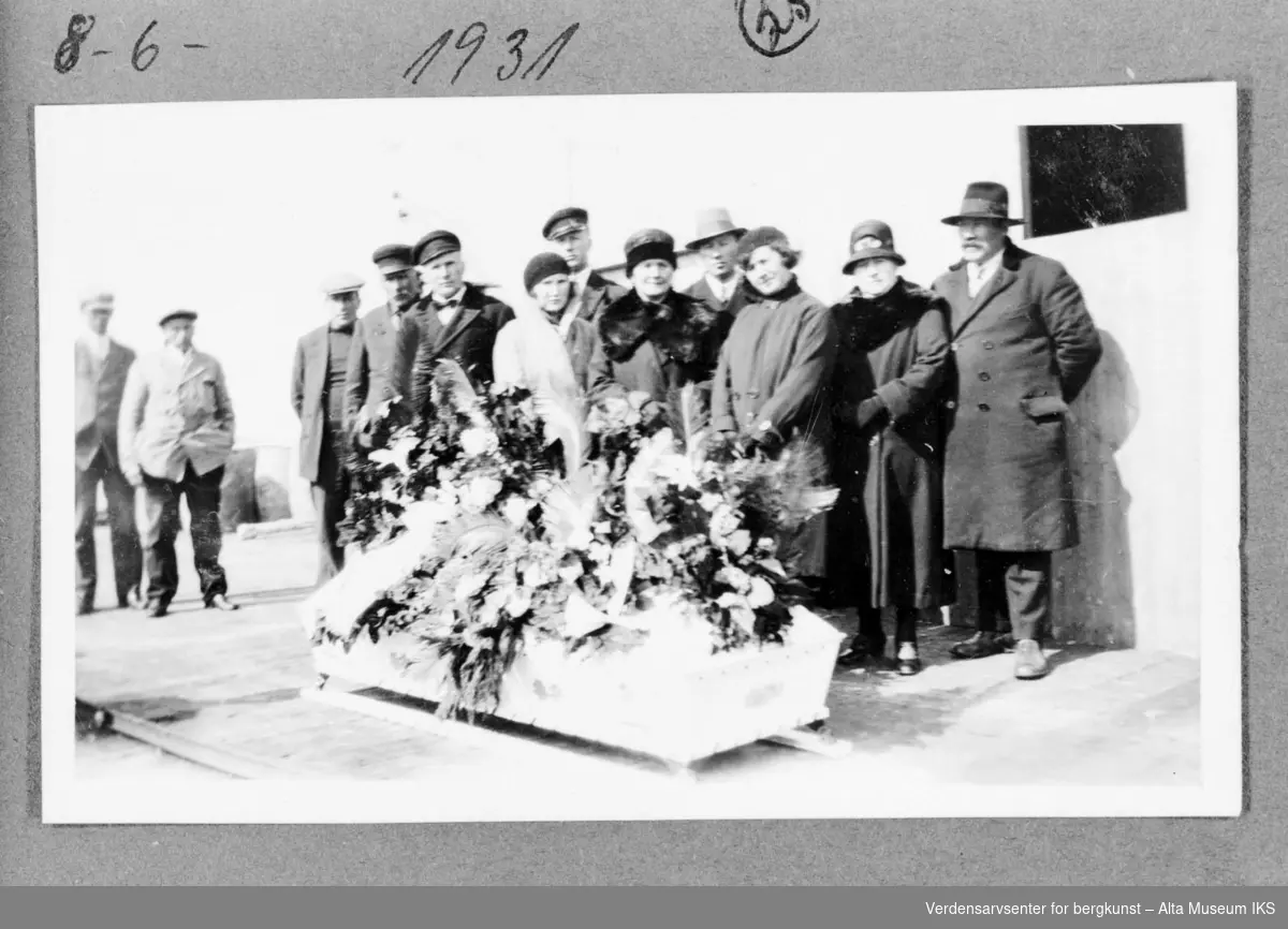 Begravelsen til Andrers Andersen, 12 personer rundt kisten med blomster.