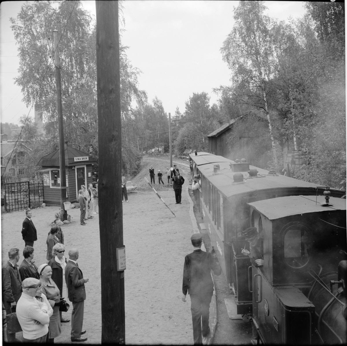 Stins vinkar klart för avresa för Museijärnvägen Östra Södermanlands Järnväg, ÖSlJ persontåg med lok "Dylta" vid Lina bruk.