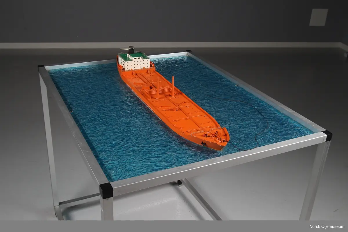 Modell av tankskip, såkalt bøyelaster - bygget i plast og montert på "sjø" av ruglet glassplate.