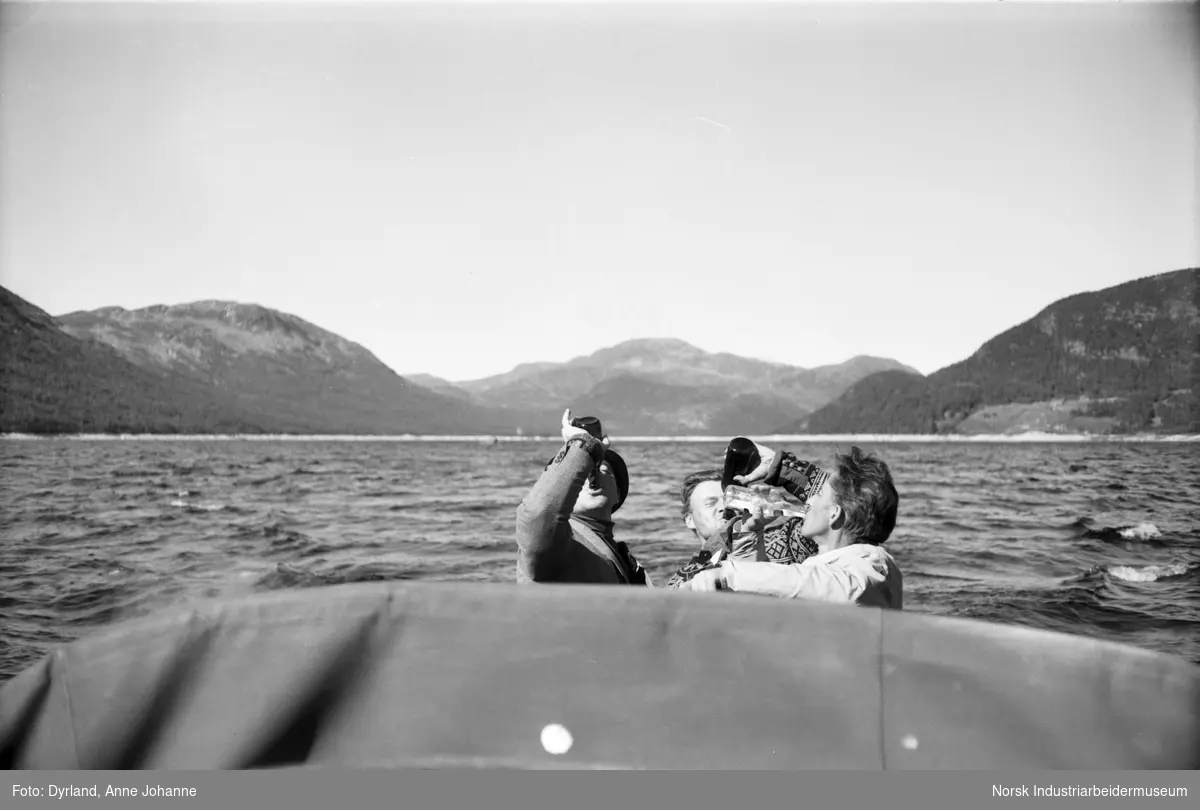 Trygve Vågen, Nils Førnes og Herman Hove drikker fra flaske i båt på Møsvatn på vei hjem fra Mogen
