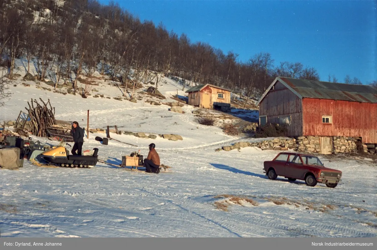 To personer, bil og snøskuter i snøen på tunet til gården Øst-Førnes på Møsstrond