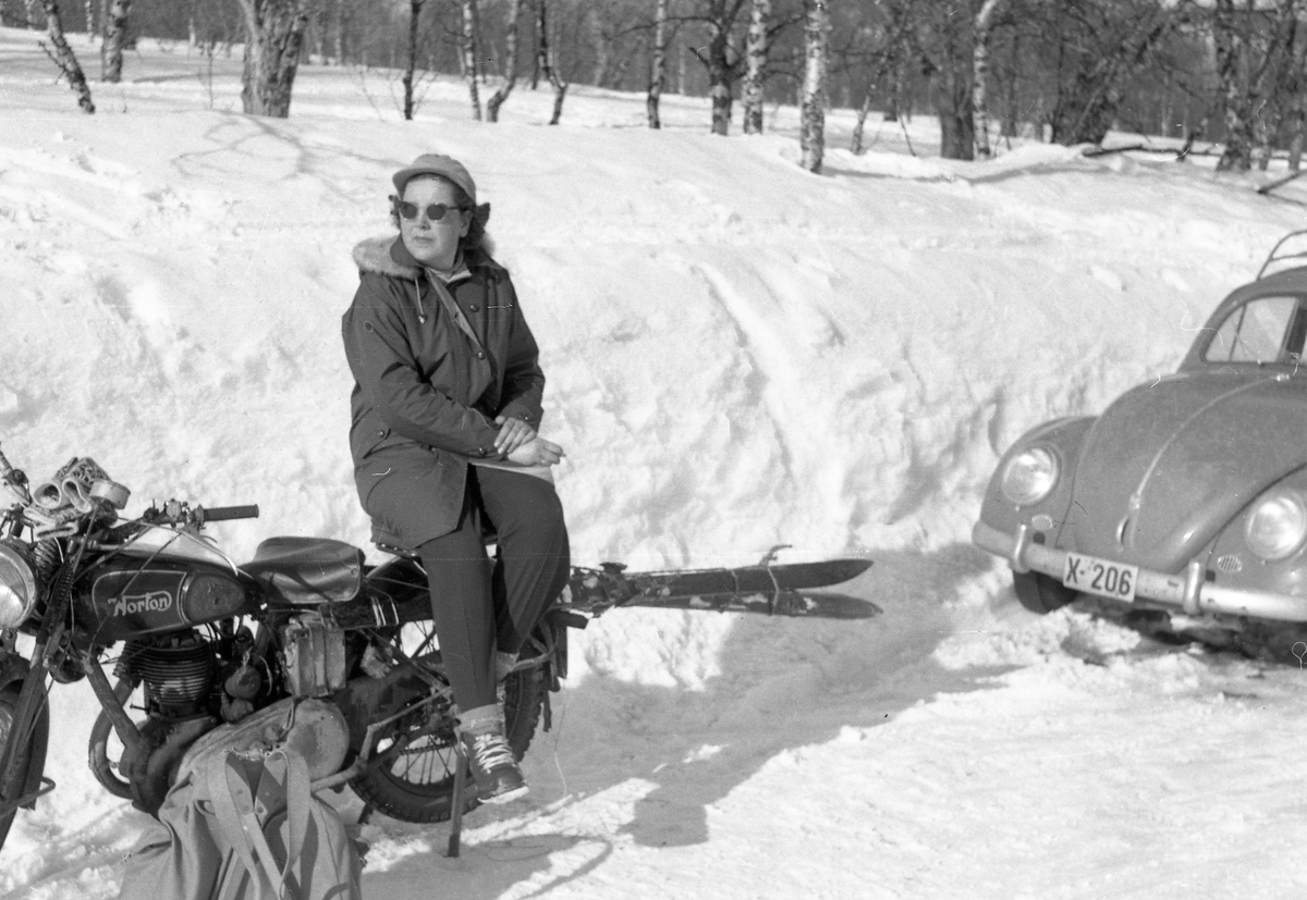 Kvinne med ski sitter på en motorsykkel.