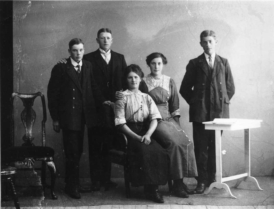 Gruppbild med tre unga män och två sittande unga kvinnor. Till vänster möjligen Einar Sandberg därnäst Anton Lundkvist som har höger hand på Einars högre axel. Mannen till höger är oidentifierad. Sittande är Rut Johansson och Edit Lindkvist.