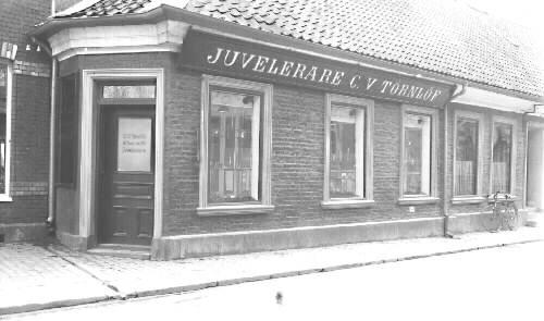 Huset uppfört efter 1823 års brand. Skyltfönster insattes 1901 men de nuvarande tillkom 1931 och 1938.  ( förslag t. bevar.)  Affären på bilden är Juvelerare C.V. Törnlöf  A T Törngrens Eftr. Nuvarande Ernst Forssell Guldsmedsaffär.